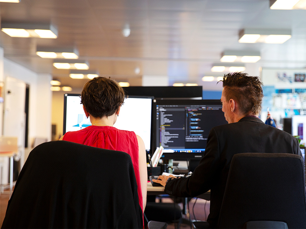 Et billede af to Debitoor medarbejdere der samarbejder på en computer